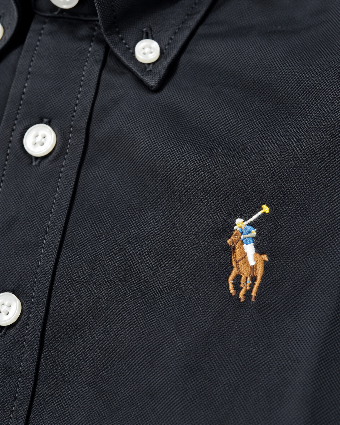 Close-up of the embroidered chest logo on the black Oxford shirt