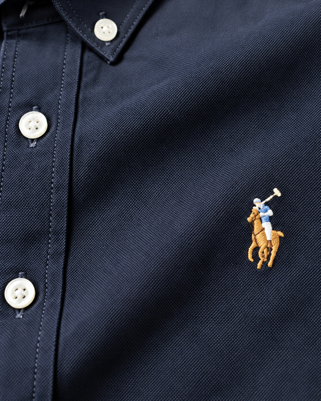 Close-up of the embroidered chest logo on the navy Oxford shirt
