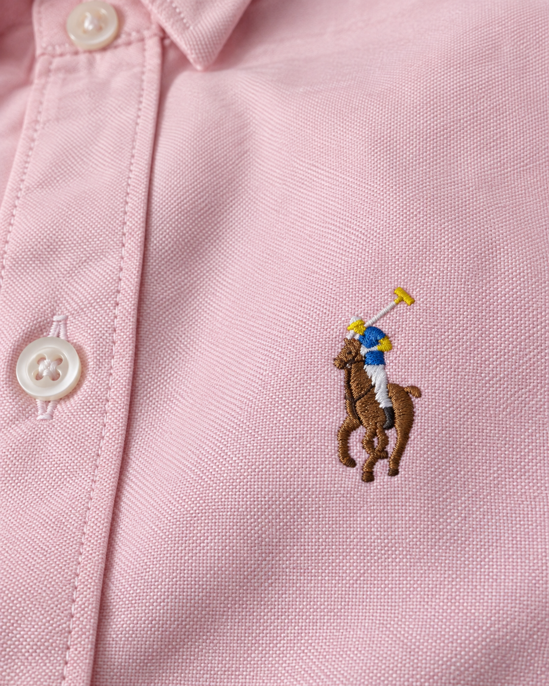 Close-up of the embroidered chest logo on the pink Oxford shirt
