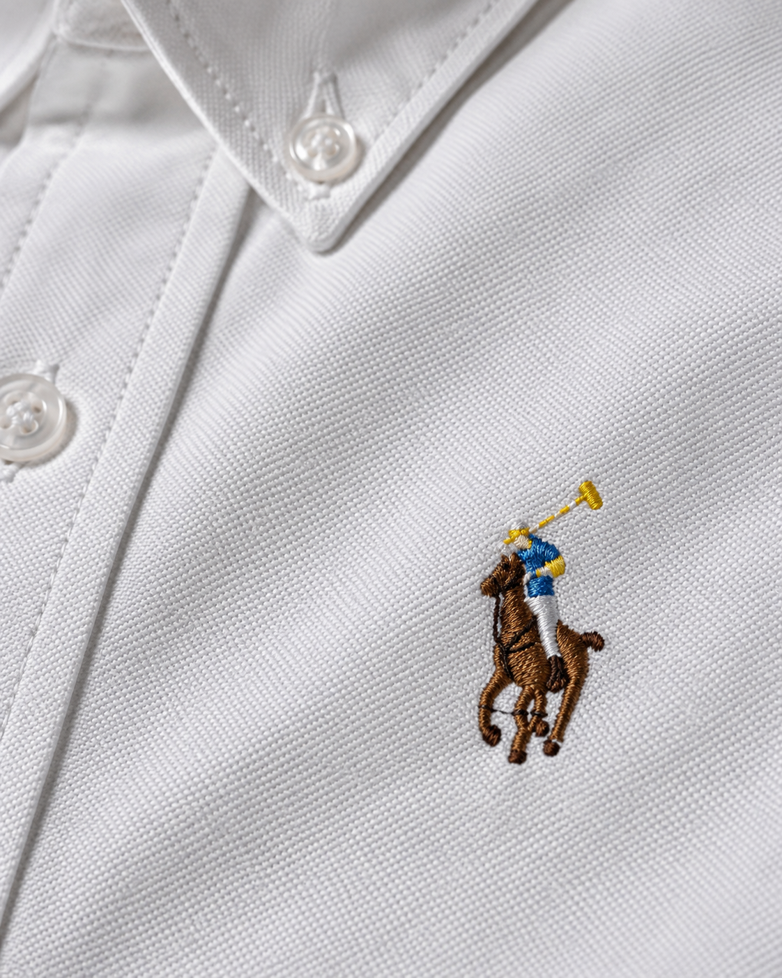 Close-up of the multicolor embroidered chest logo on the white Oxford shirt
